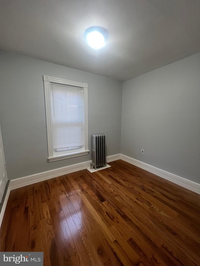 empty room with wood-type flooring and radiator