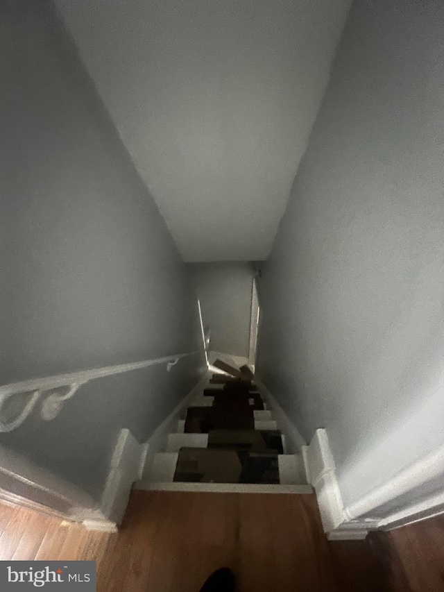 stairway featuring vaulted ceiling and hardwood / wood-style floors