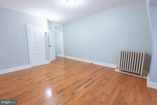 spare room featuring radiator and hardwood / wood-style floors