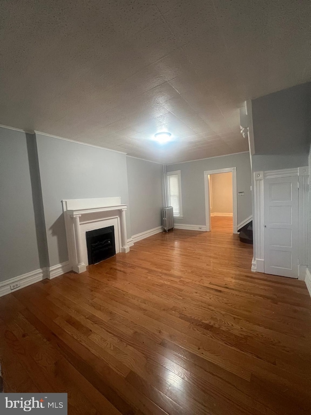 unfurnished living room with wood-type flooring and radiator heating unit