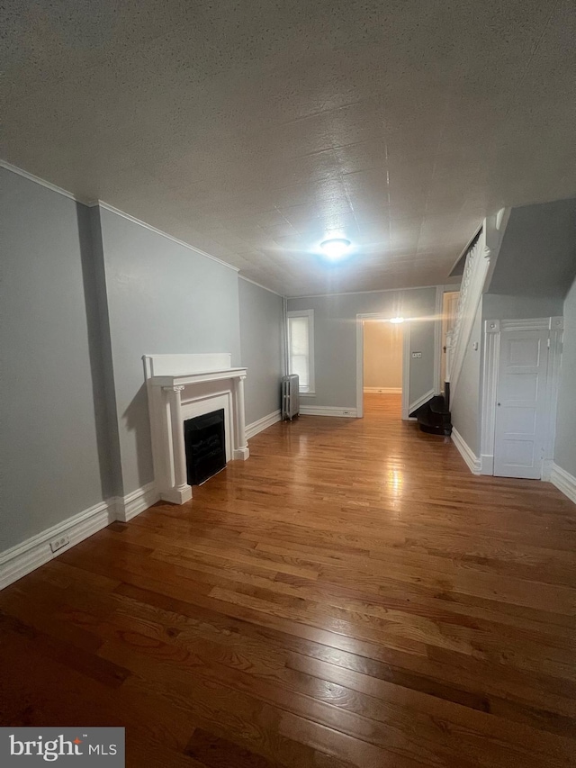 unfurnished living room featuring hardwood / wood-style flooring and radiator heating unit