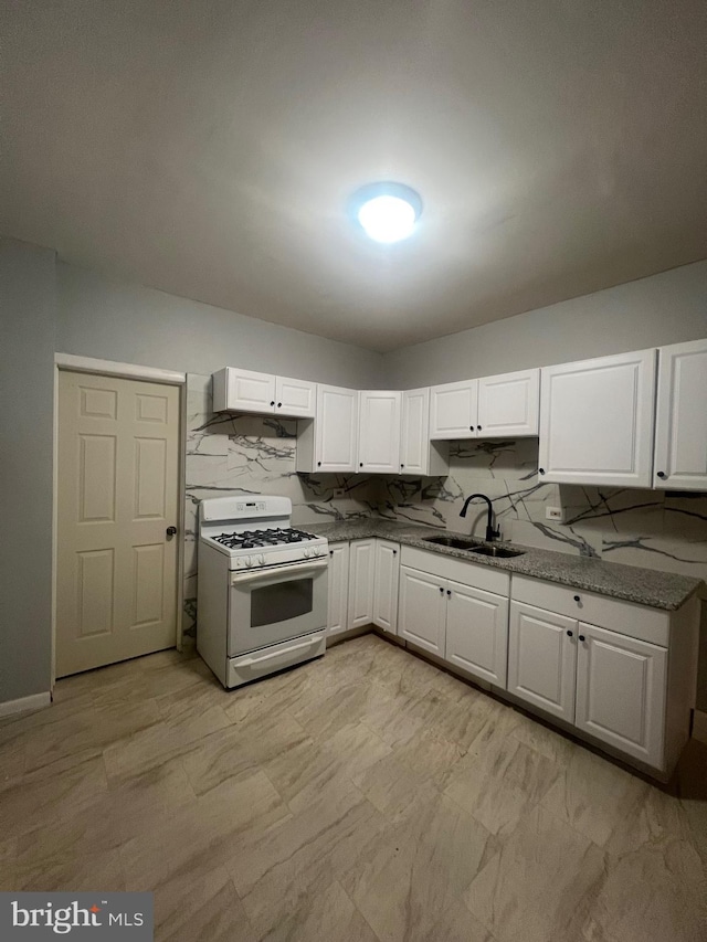 kitchen with white range with gas cooktop, sink, white cabinets, and backsplash