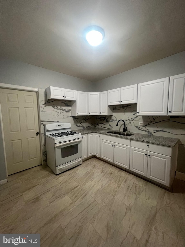 kitchen featuring white range with gas cooktop, sink, backsplash, and white cabinets