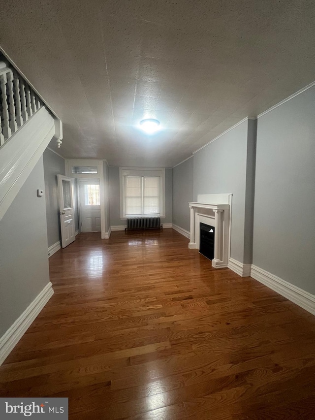 unfurnished living room featuring radiator heating unit, dark hardwood / wood-style floors, and a textured ceiling