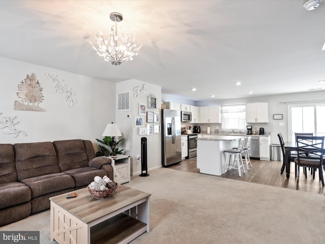 living room featuring plenty of natural light, light carpet, and a notable chandelier