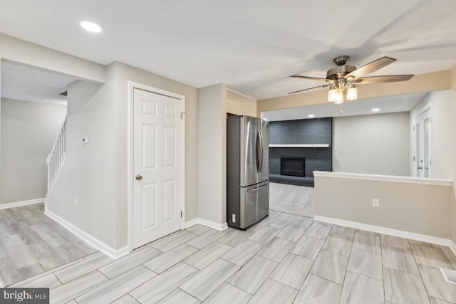 kitchen with stainless steel refrigerator, ceiling fan, and a fireplace