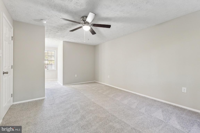 empty room with ceiling fan, light carpet, and a textured ceiling