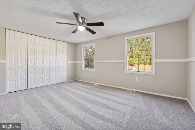 unfurnished bedroom featuring ceiling fan, a closet, carpet, and a textured ceiling