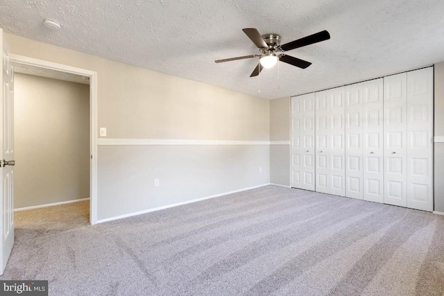 unfurnished bedroom featuring ceiling fan, light colored carpet, a closet, and a textured ceiling