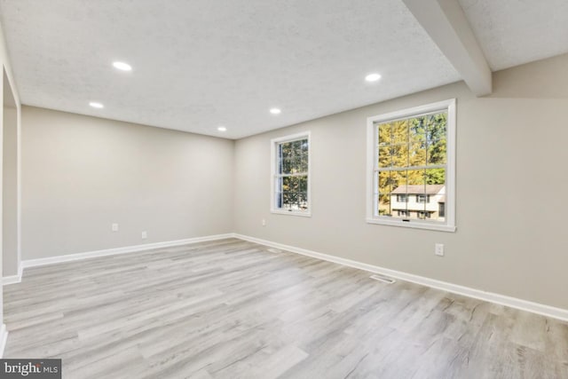 interior space with beam ceiling, a textured ceiling, and light wood-type flooring