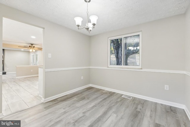 spare room featuring ceiling fan with notable chandelier, a textured ceiling, and light hardwood / wood-style floors