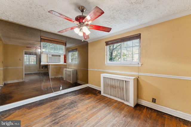 unfurnished room with radiator, ceiling fan, cooling unit, a textured ceiling, and dark hardwood / wood-style flooring