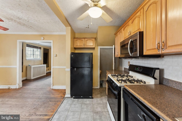 kitchen with light tile patterned flooring, crown molding, black appliances, ceiling fan, and backsplash