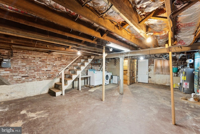 basement with water heater, brick wall, and independent washer and dryer