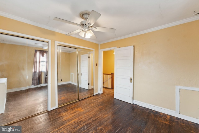 unfurnished bedroom featuring ornamental molding, dark wood-type flooring, two closets, and ceiling fan