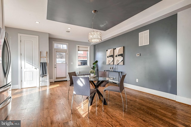 dining space with a raised ceiling and light hardwood / wood-style floors