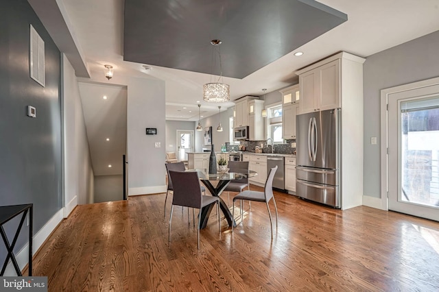 dining area featuring a raised ceiling, plenty of natural light, hardwood / wood-style flooring, and sink