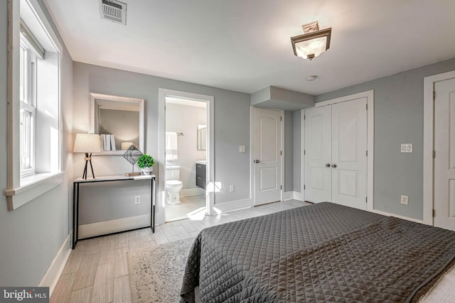 bedroom featuring multiple windows, connected bathroom, and light hardwood / wood-style floors