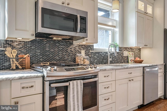 kitchen featuring white cabinetry, stainless steel appliances, sink, and light stone counters