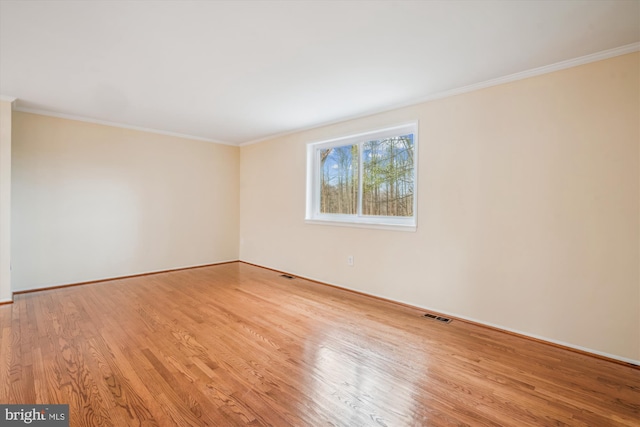 spare room featuring crown molding and light hardwood / wood-style flooring