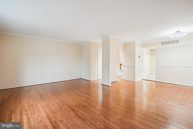 spare room featuring ornamental molding and light hardwood / wood-style flooring