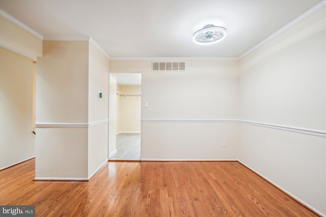 empty room with crown molding and light hardwood / wood-style floors