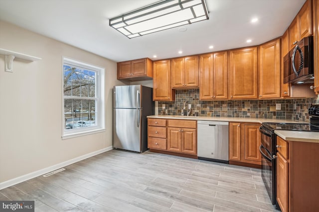 kitchen with backsplash, light hardwood / wood-style flooring, stainless steel appliances, and sink