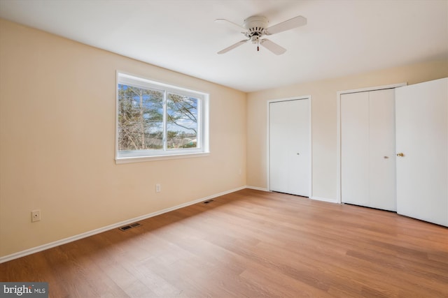 unfurnished bedroom with two closets and light wood-type flooring