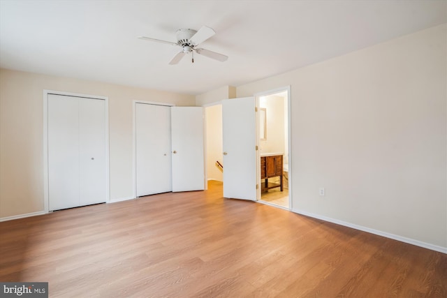 unfurnished bedroom with connected bathroom, light hardwood / wood-style floors, multiple closets, and ceiling fan