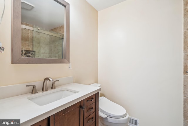 bathroom featuring vanity, toilet, and a shower with shower door