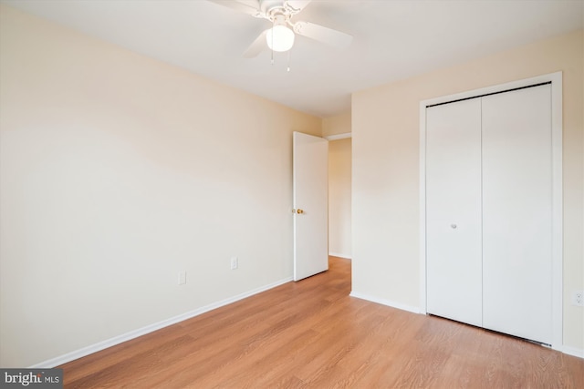 unfurnished bedroom with ceiling fan, light wood-type flooring, and a closet