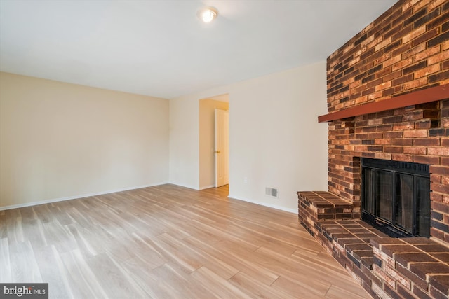 unfurnished living room with a fireplace and light hardwood / wood-style floors