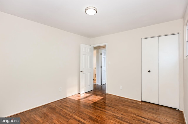 unfurnished bedroom with dark hardwood / wood-style flooring and a closet