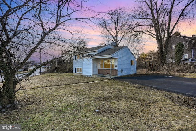 property exterior at dusk featuring a lawn