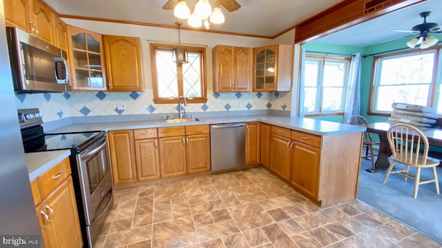 kitchen featuring sink, ceiling fan, stainless steel appliances, a healthy amount of sunlight, and decorative light fixtures