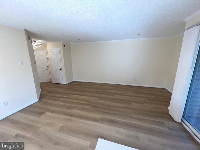 empty room featuring wood-type flooring, ornamental molding, and a textured ceiling