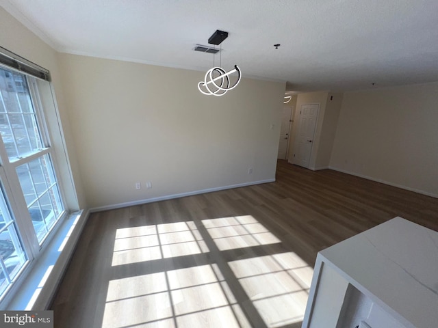 unfurnished dining area featuring an inviting chandelier, a wealth of natural light, and dark hardwood / wood-style flooring