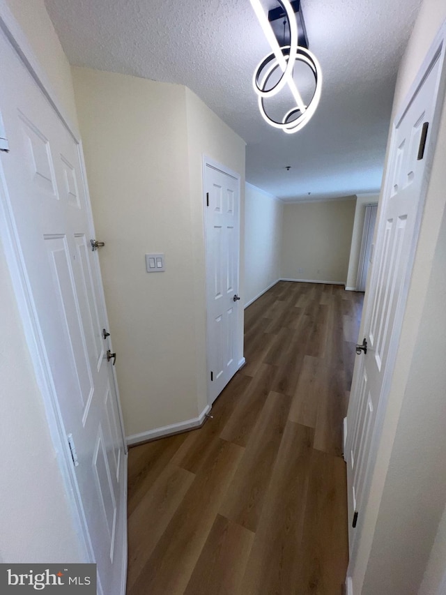 corridor with dark wood-type flooring and a textured ceiling