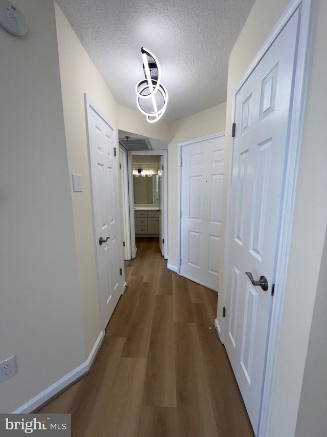 corridor featuring a textured ceiling and dark hardwood / wood-style flooring