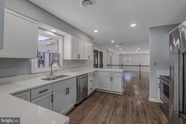 kitchen featuring appliances with stainless steel finishes, sink, white cabinets, and kitchen peninsula