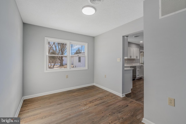 empty room with hardwood / wood-style floors and a textured ceiling