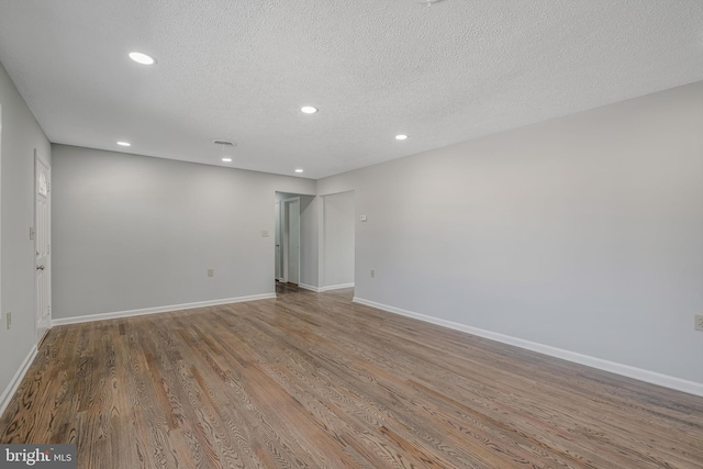 empty room with hardwood / wood-style floors and a textured ceiling