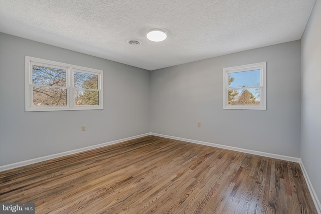 spare room featuring wood-type flooring and a textured ceiling