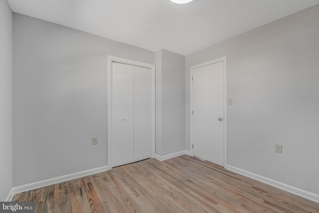 unfurnished bedroom with light wood-type flooring and a closet