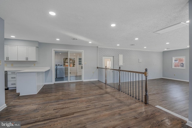 kitchen with brick wall, dark hardwood / wood-style flooring, a textured ceiling, and white cabinets