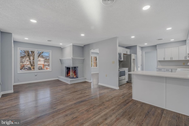 unfurnished living room featuring dark hardwood / wood-style floors, a textured ceiling, and a multi sided fireplace