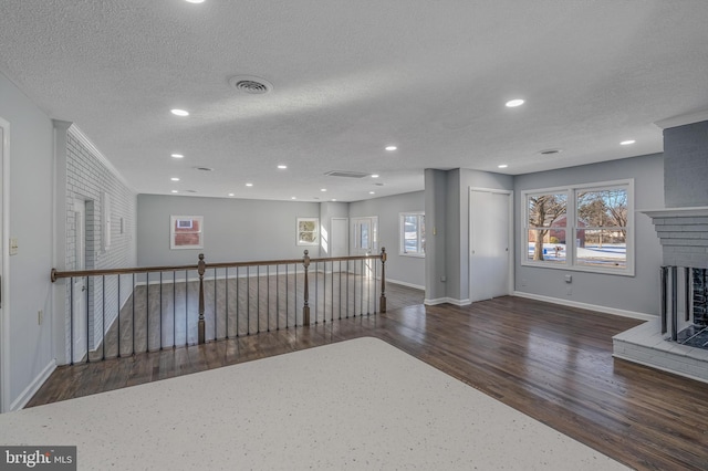 interior space featuring a brick fireplace, dark hardwood / wood-style floors, and a textured ceiling