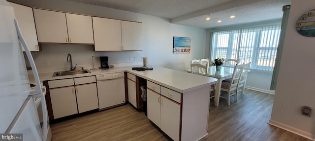 kitchen with white cabinetry, sink, white appliances, kitchen peninsula, and a textured ceiling