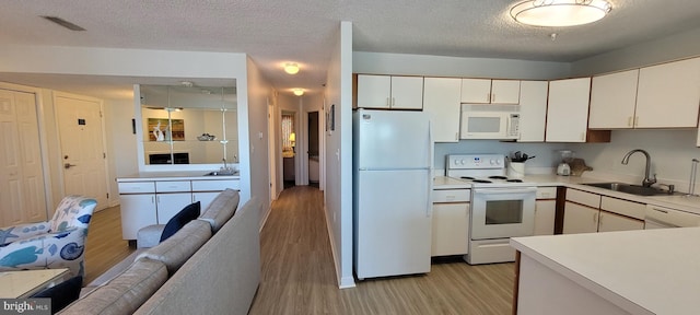 kitchen with sink, white cabinetry, a textured ceiling, light wood-type flooring, and white appliances