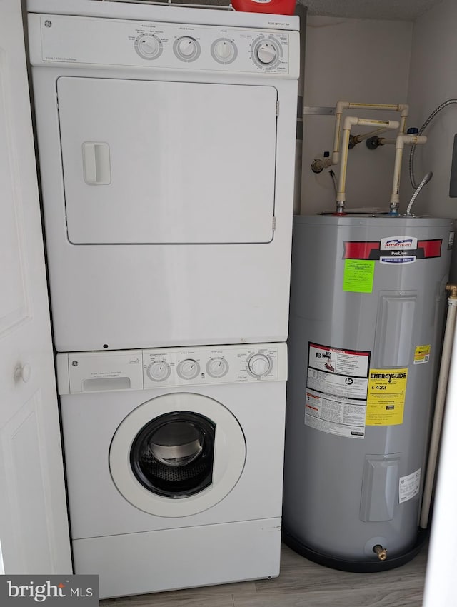 clothes washing area featuring light hardwood / wood-style flooring, electric water heater, and stacked washer / dryer